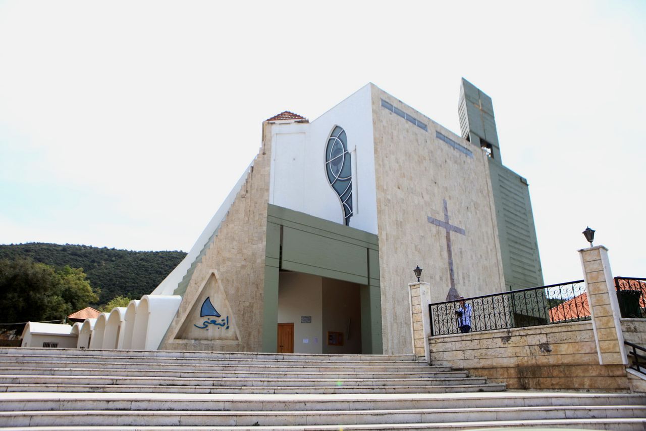 The church of Saydet el Ghessaleh in Kobayat: a stone facade with a large cross and tower above a wide flight of steps