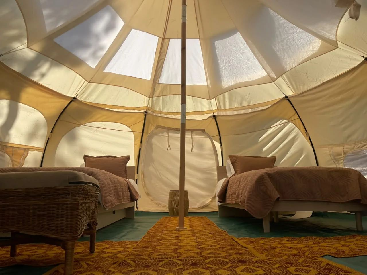 Inside a Lotus Belle tent: two beds under the canvas roof with its clear panels and centre pole