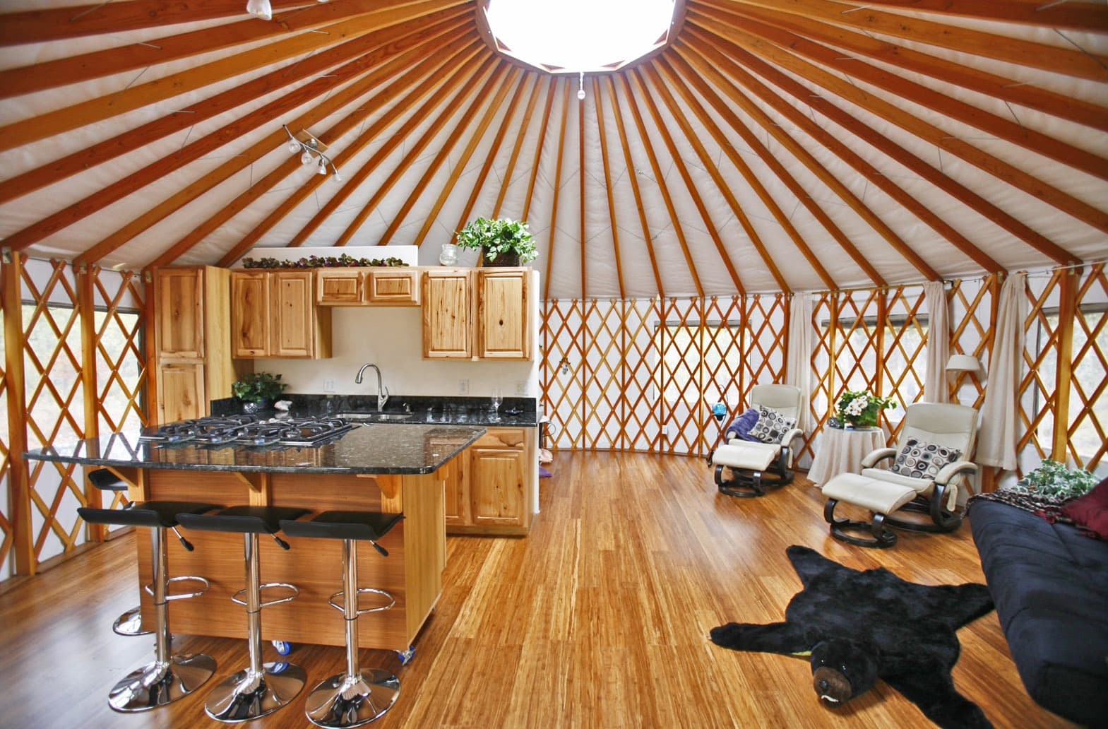 Spacious yurt interior with full kitchen, lounge area, and natural wood design at Horizon Pines