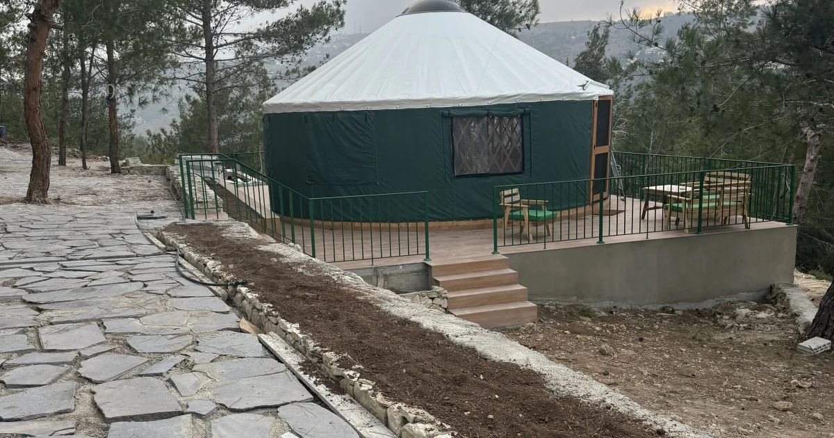 A Premium Yurt at Horizon Pines seen from the stone path, with its terrace and the pine forest behind