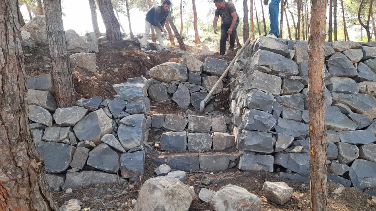 Traditional stone terrace and steps under construction among the pine trees at Horizon Pines in Kobayat.