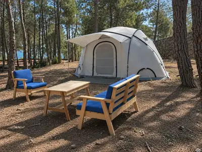 Dome tent and cushioned wooden seating beside a stone wall, with a view through the pines