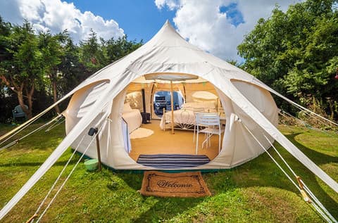 Luxury Lotus Belle tent set up on green grass at Horizon Pines in Lebanon, featuring cozy interiors, a welcome mat, and open-air glamping setup under blue skies.