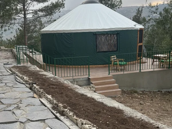 The yurt on its terrace with outdoor seating, looking over the valley