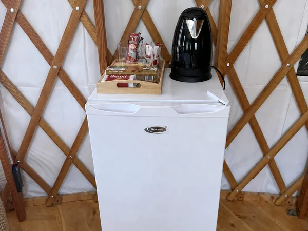 The in-yurt fridge, with a kettle and a welcome tray of tea and coffee