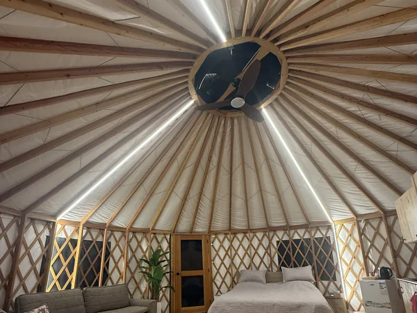 Looking up at the domed roof and ceiling fan, with the bed and sofa below