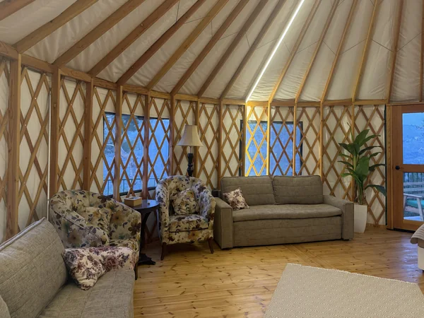 The yurt lit up after dark, bed made up under the lattice wall
